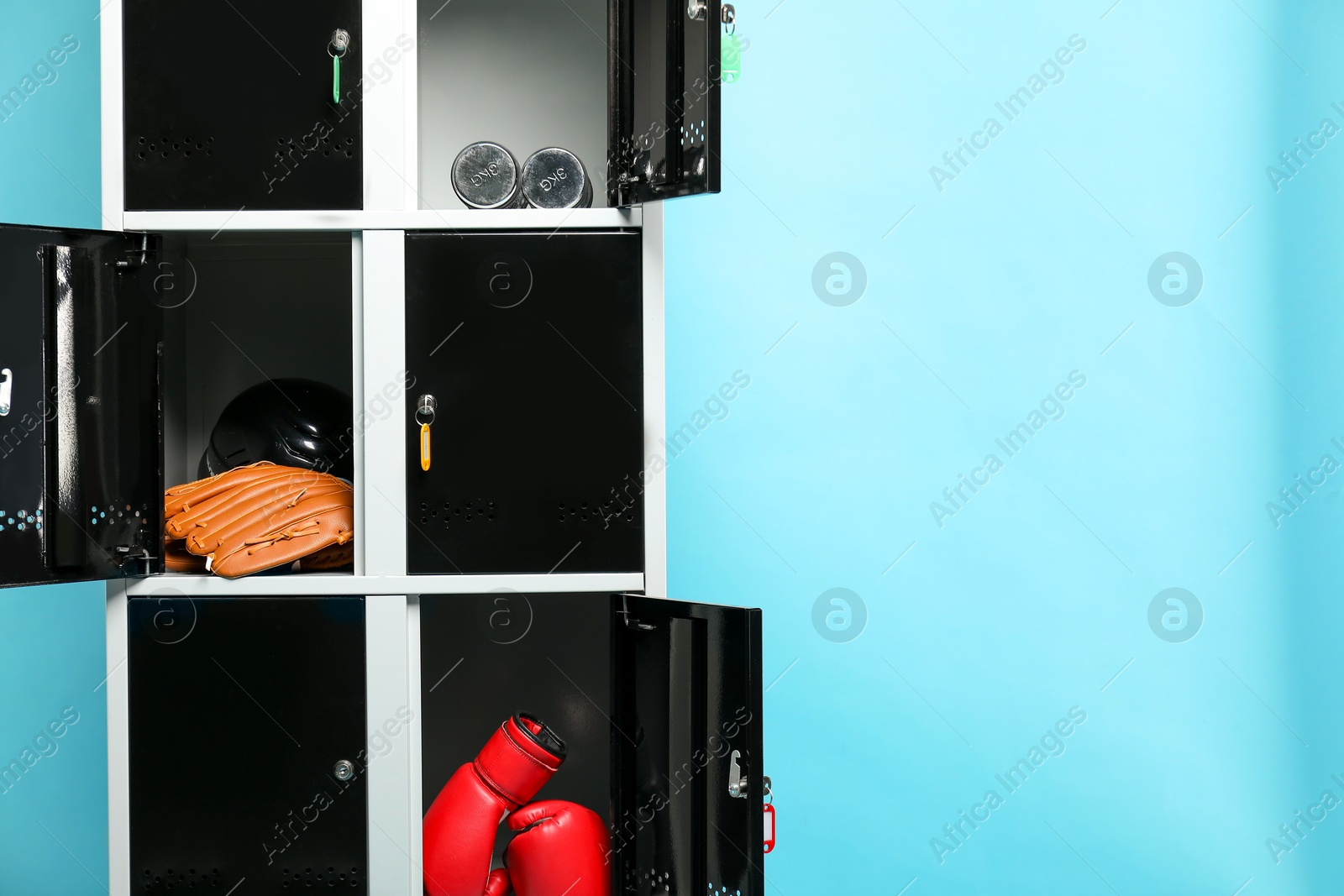 Photo of Open lockers with sport equipment on light blue background, space for text