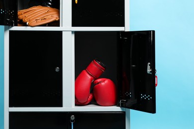 Open lockers with sport equipment on light blue background