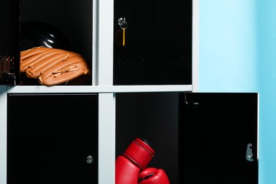 Photo of Open lockers with sport equipment on light blue background, closeup