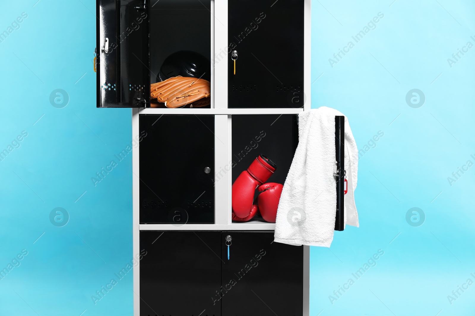 Photo of Open lockers with sport equipment on light blue background