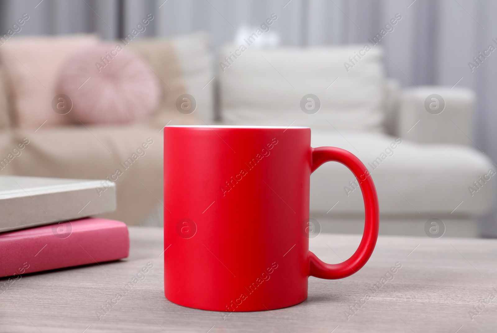 Photo of Blank red ceramic mug and notebooks on wooden table. Mockup for design