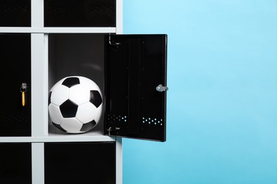 Photo of Open locker with soccer ball on light blue background, space for text