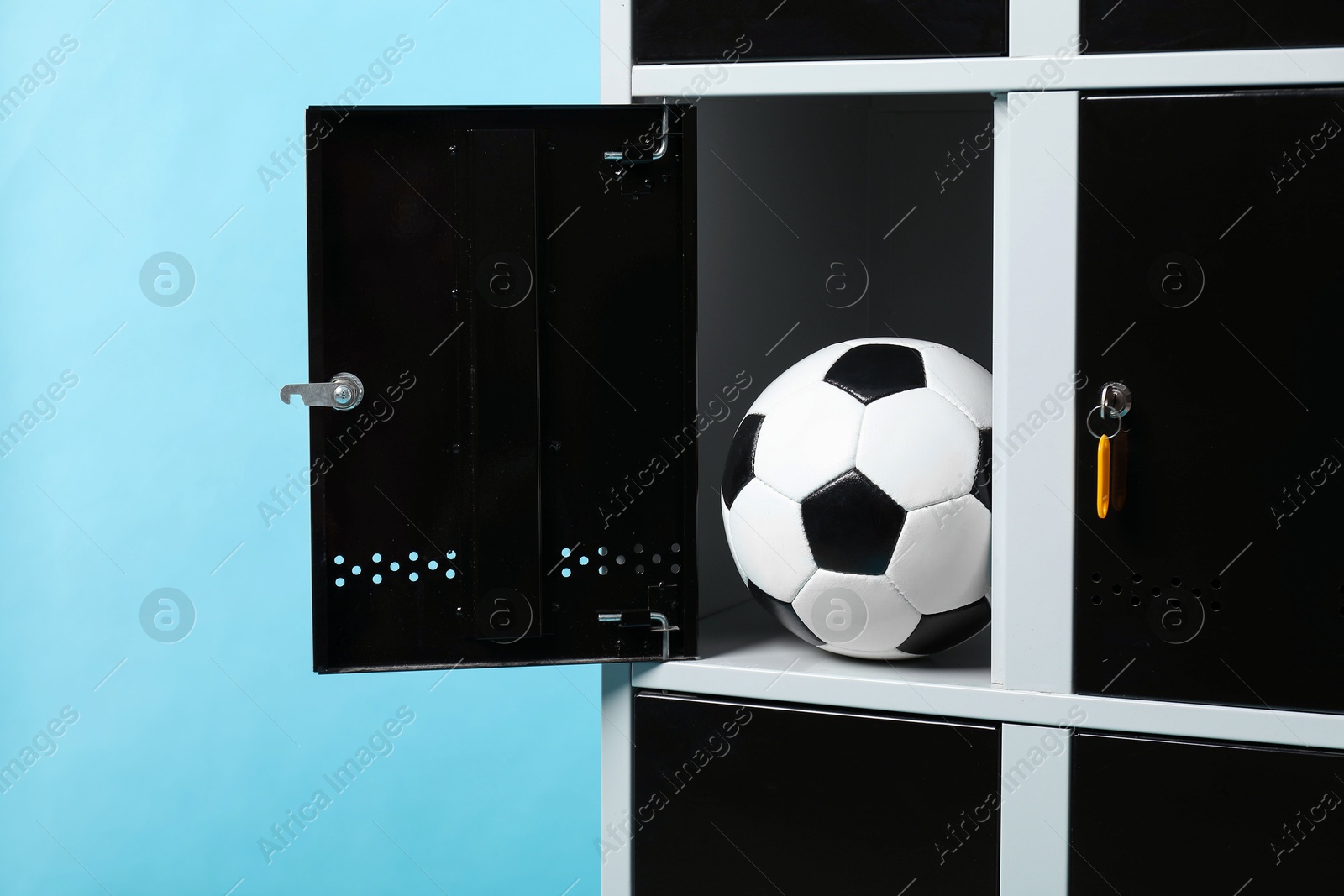 Photo of Open locker with soccer ball on light blue background