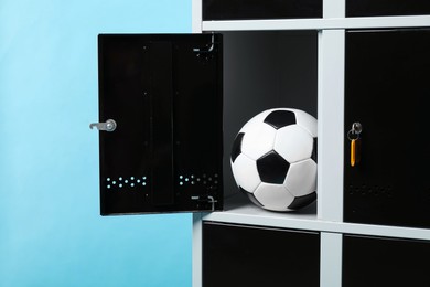 Photo of Open locker with soccer ball on light blue background