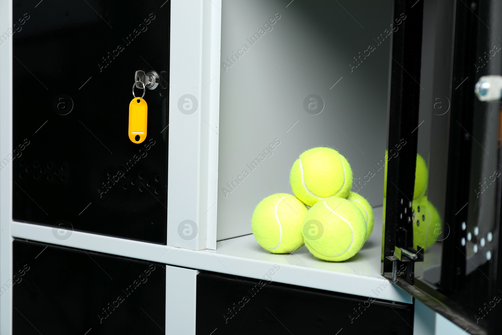 Photo of Open locker with tennis balls and key, closeup