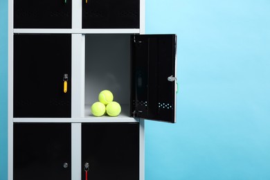 Photo of Open locker with tennis balls on light blue background, space for text