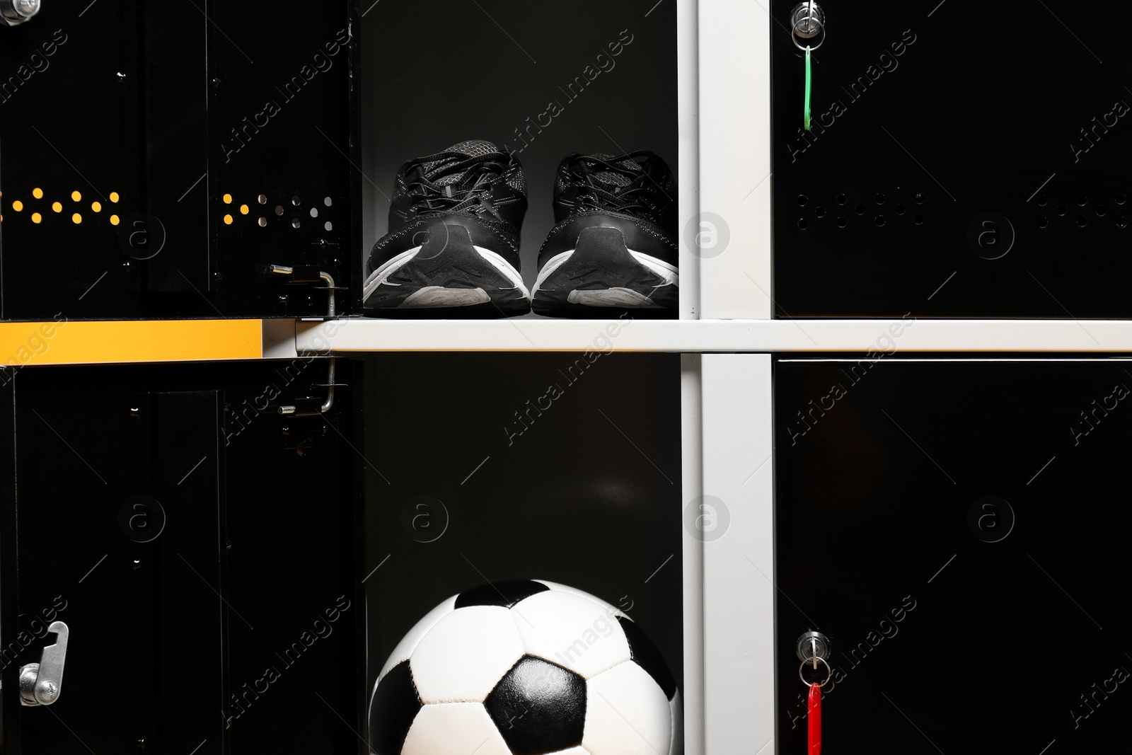 Photo of Open lockers with sneakers and soccer ball, closeup