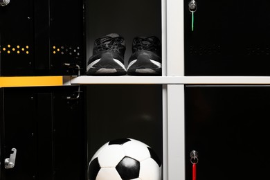 Photo of Open lockers with sneakers and soccer ball, closeup