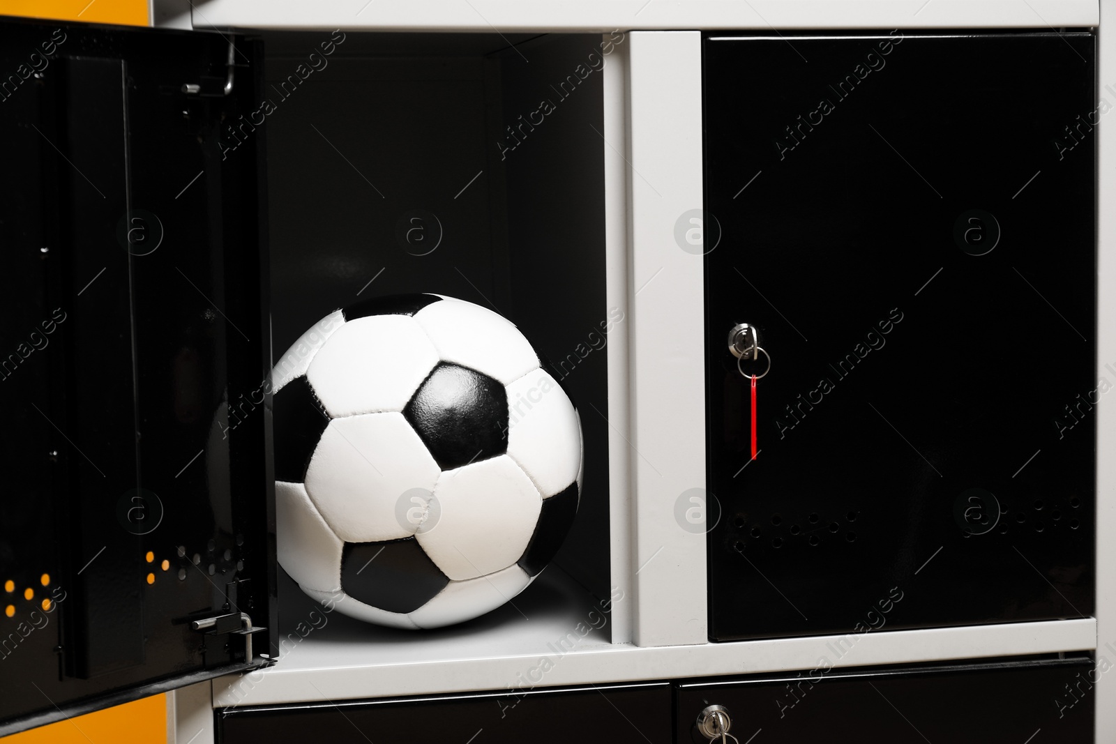 Photo of Open locker with soccer ball on orange background, closeup