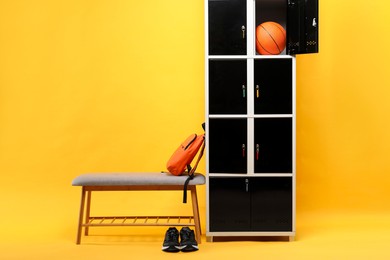 Open locker with basketball ball, bench, backpack and sneakers on orange background