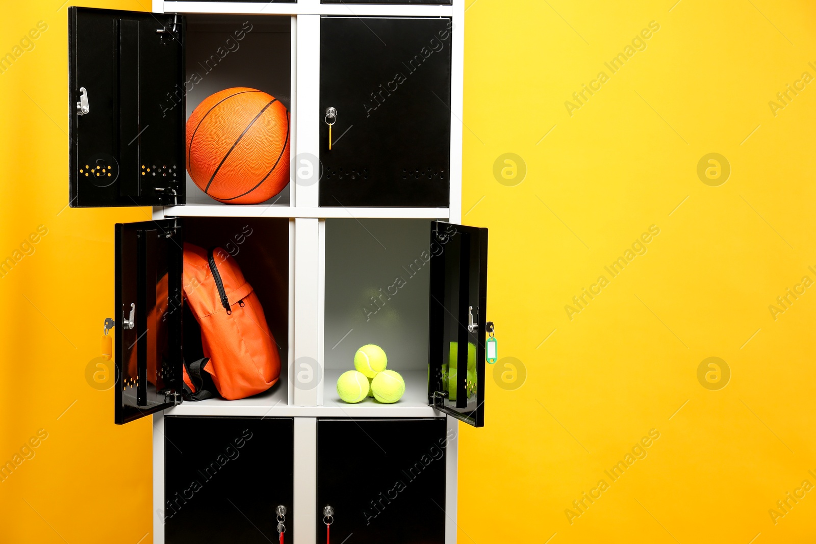 Photo of Open lockers with sport equipment on orange background, space for text