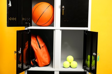 Photo of Open lockers with sport equipment on orange background