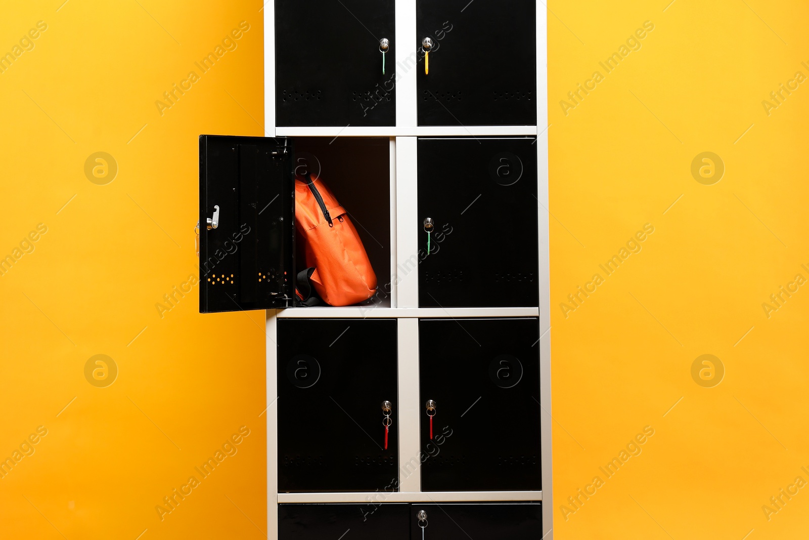 Photo of Open locker with backpack on orange background