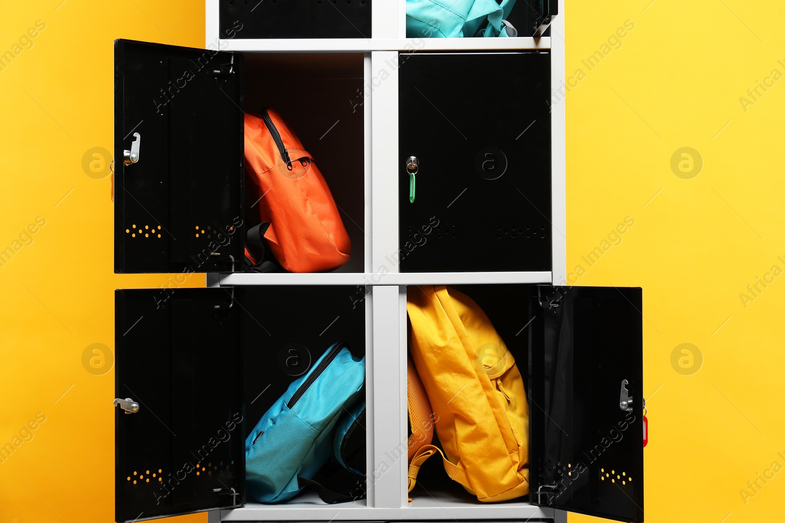 Photo of Lockers with different backpacks on orange background