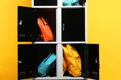 Lockers with different backpacks on orange background