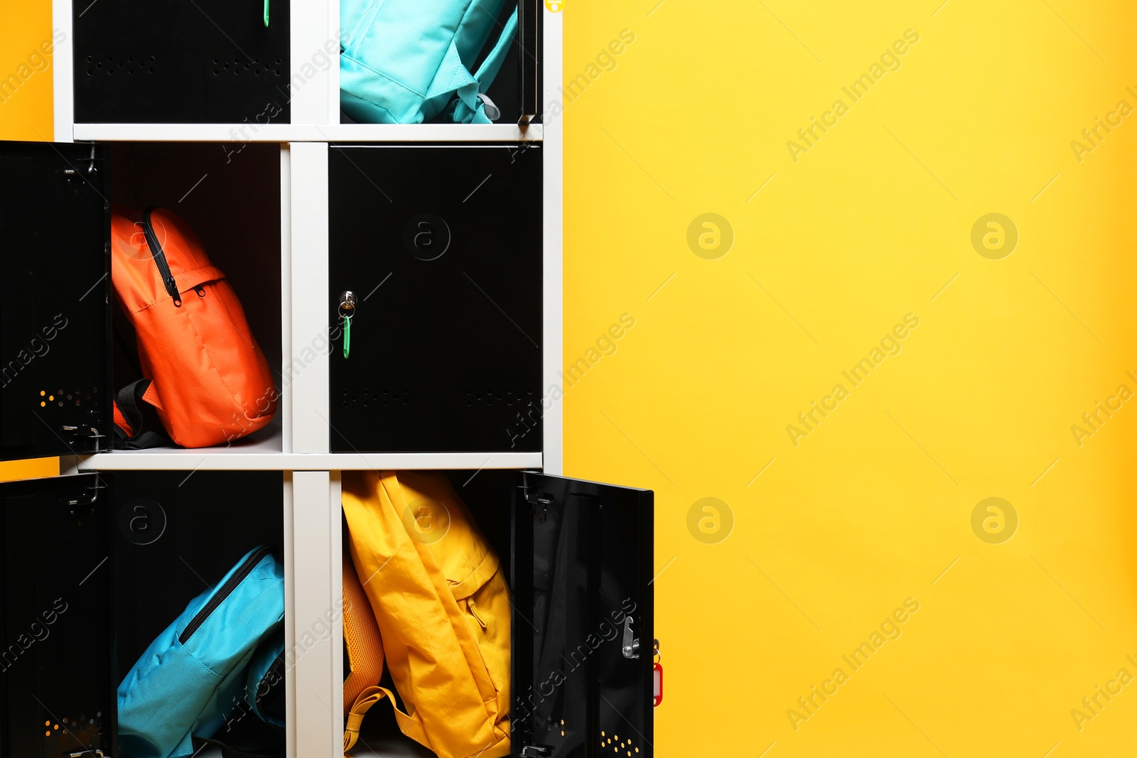 Photo of Lockers with different backpacks on orange background, space for text