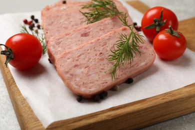 Photo of Pieces of tasty canned meat, dill, peppercorns and tomatoes on grey table, closeup