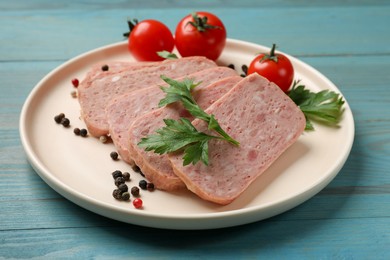 Photo of Pieces of tasty canned meat, parsley, peppercorns and tomatoes on light blue wooden table, closeup