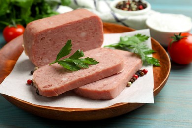 Photo of Pieces of tasty canned meat, parsley and peppercorns on light blue wooden table, closeup