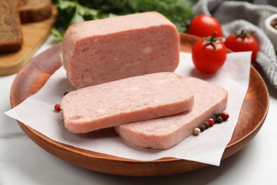 Pieces of tasty canned meat and peppercorns on white table, closeup