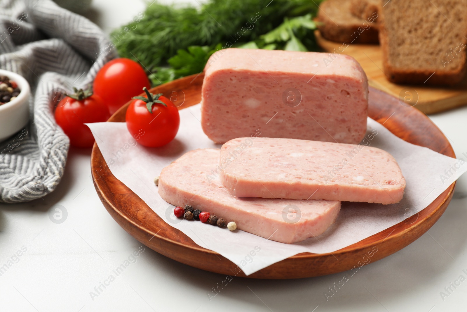 Photo of Pieces of tasty canned meat and peppercorns on white table, closeup