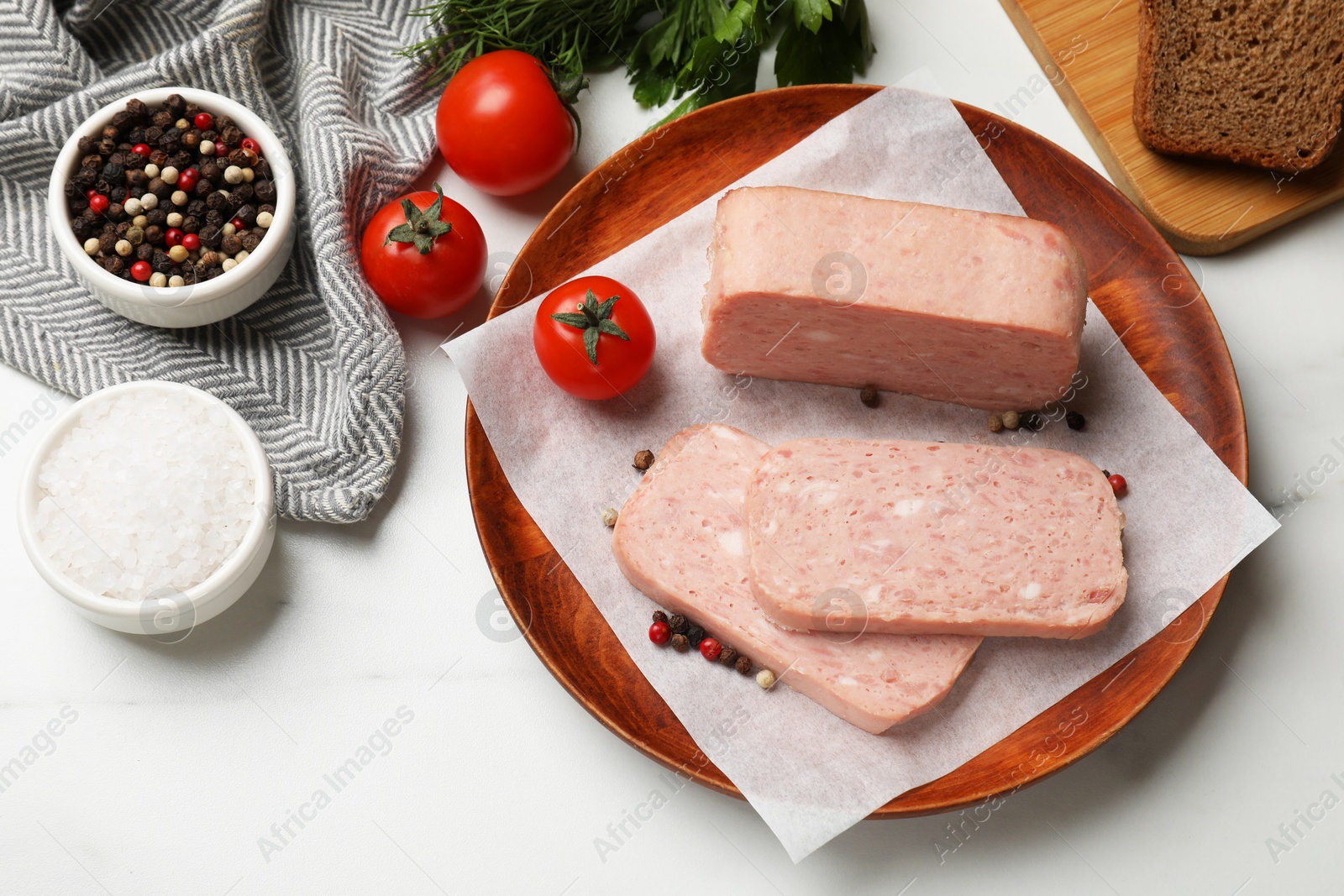 Photo of Pieces of tasty canned meat, tomatoes and spices on white table, flat lay