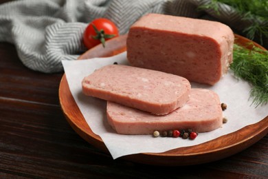 Photo of Pieces of tasty canned meat and peppercorns on wooden table, closeup