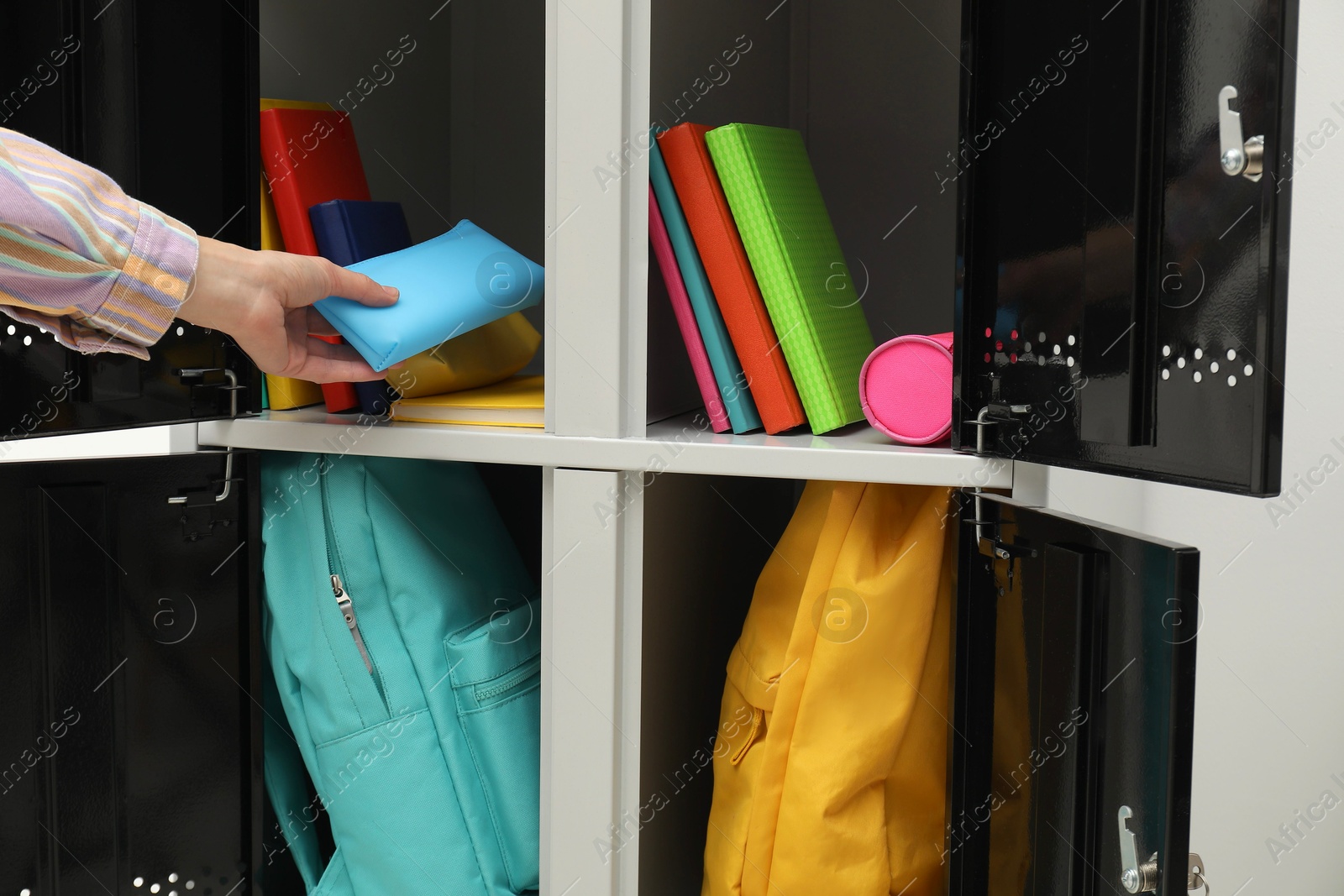 Photo of Woman putting stationery case into locker, closeup