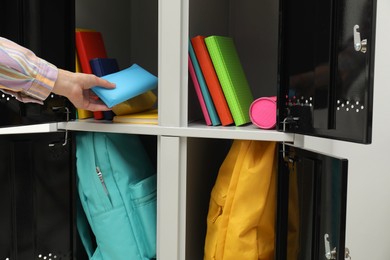 Photo of Woman putting stationery case into locker, closeup