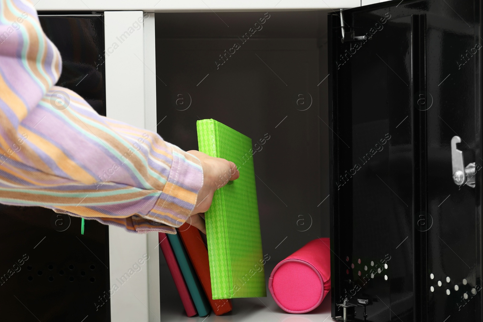 Photo of Woman putting book into locker, closeup view