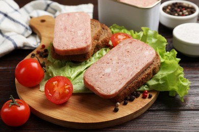 Photo of Tasty canned meat, bread, tomatoes, spices and lettuce on wooden table, closeup