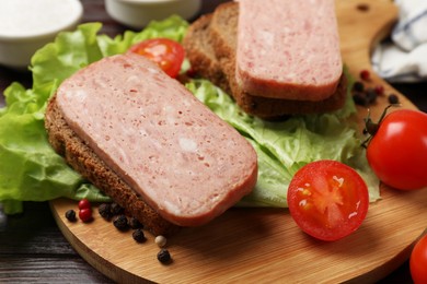 Photo of Tasty canned meat, bread, tomatoes, spices and lettuce on wooden table, closeup