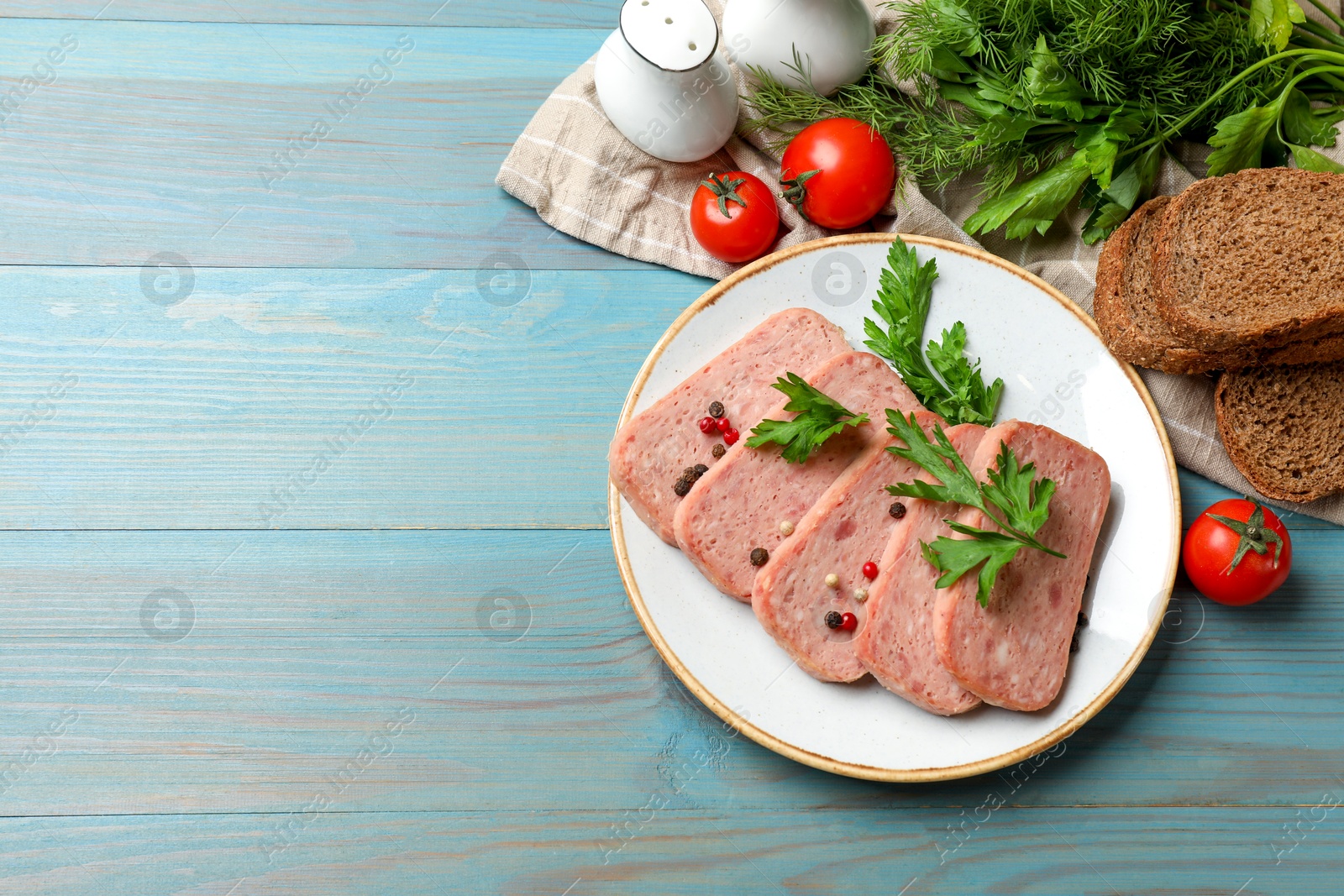 Photo of Tasty canned meat, spices, bread and tomatoes on light blue wooden table, flat lay. Space for text