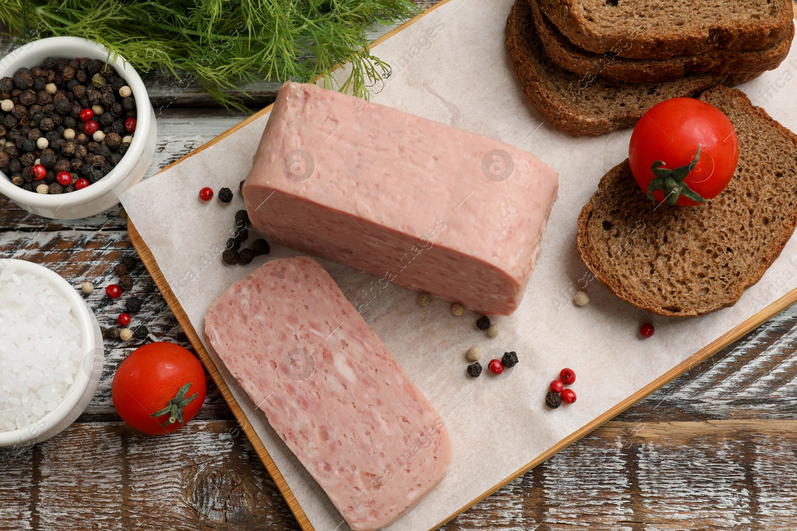 Photo of Canned meat, spices, tomatoes and bread on wooden table, flat lay