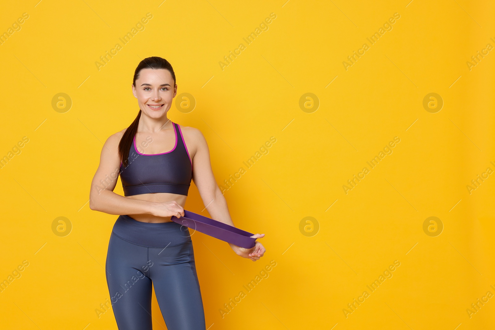 Photo of Smiling woman with resistance band on yellow background. Space for text