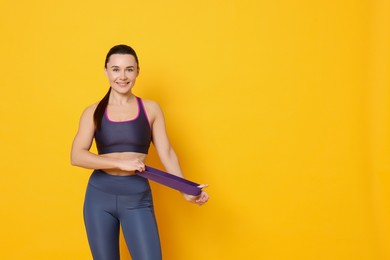 Photo of Smiling woman with resistance band on yellow background. Space for text