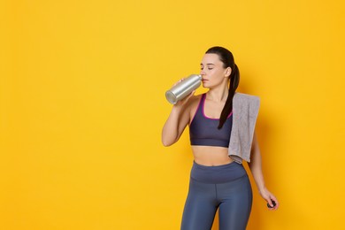 Photo of Beautiful woman with thermo bottle and towel on yellow background. Space for text