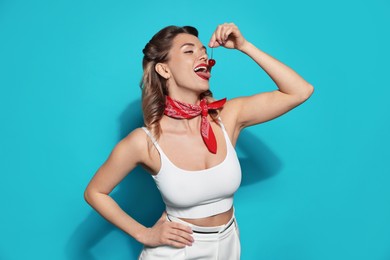 Photo of Attractive pin-up woman with cherry on light blue background