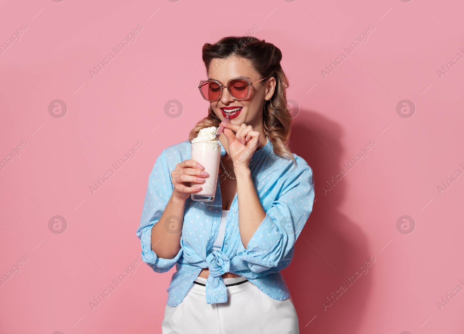 Photo of Happy pin-up woman with milk shake on pink background