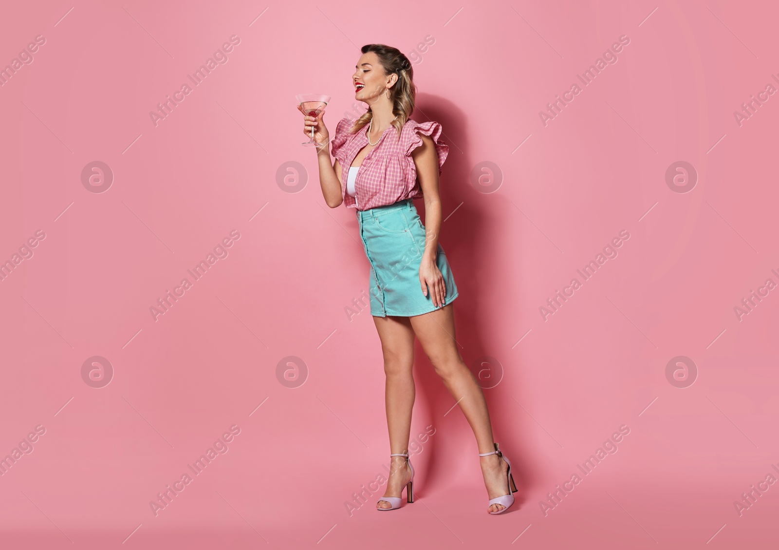 Photo of Happy pin-up woman with cocktail on pink background