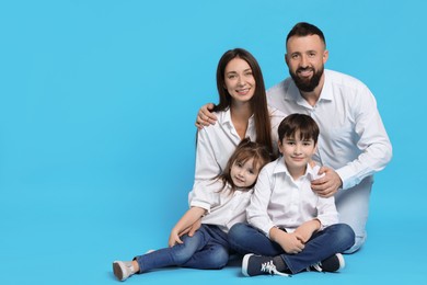 Photo of Happy parents and their children on light blue background, space for text