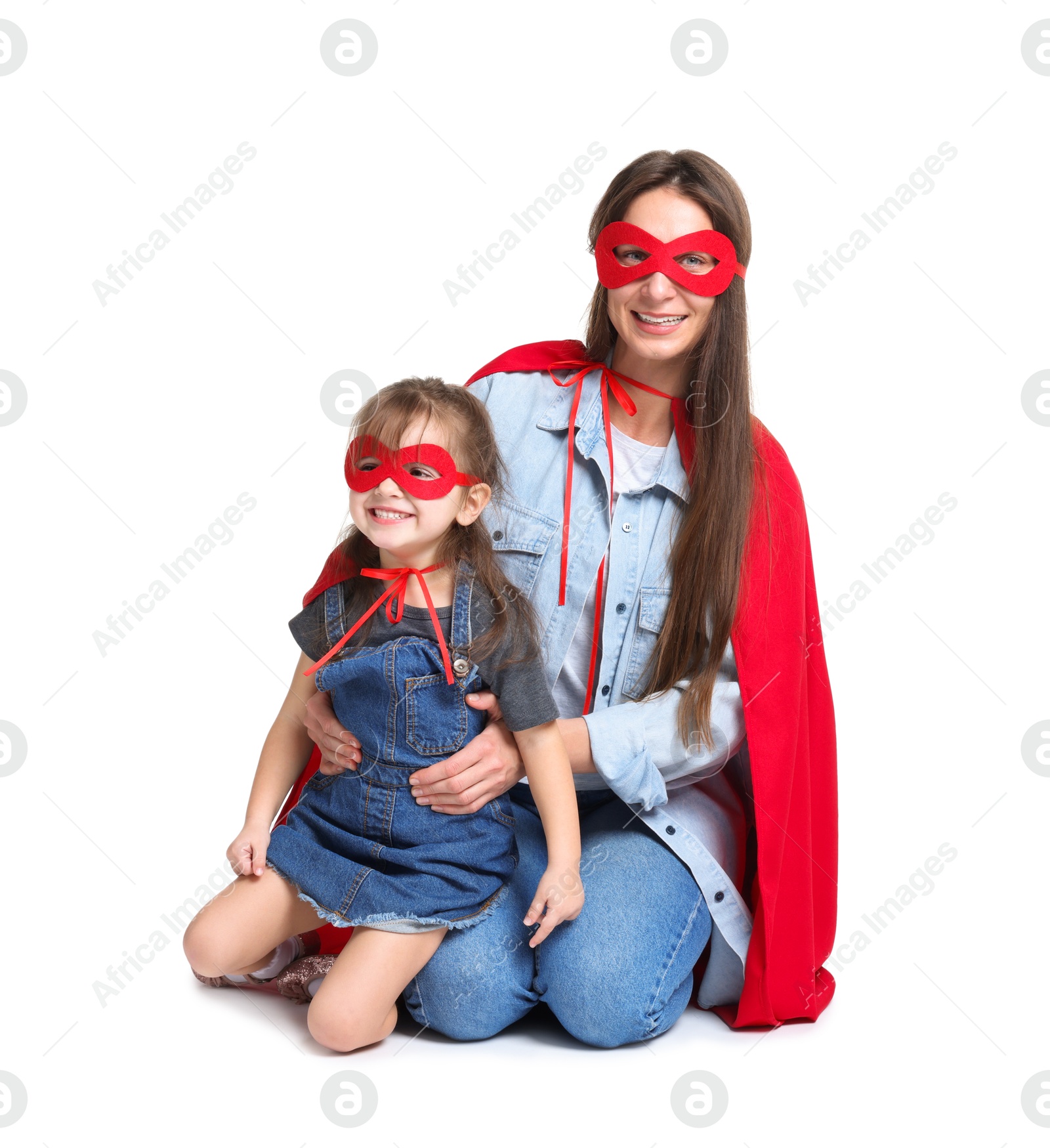 Photo of Mother and her cute little daughter wearing superhero costumes on white background