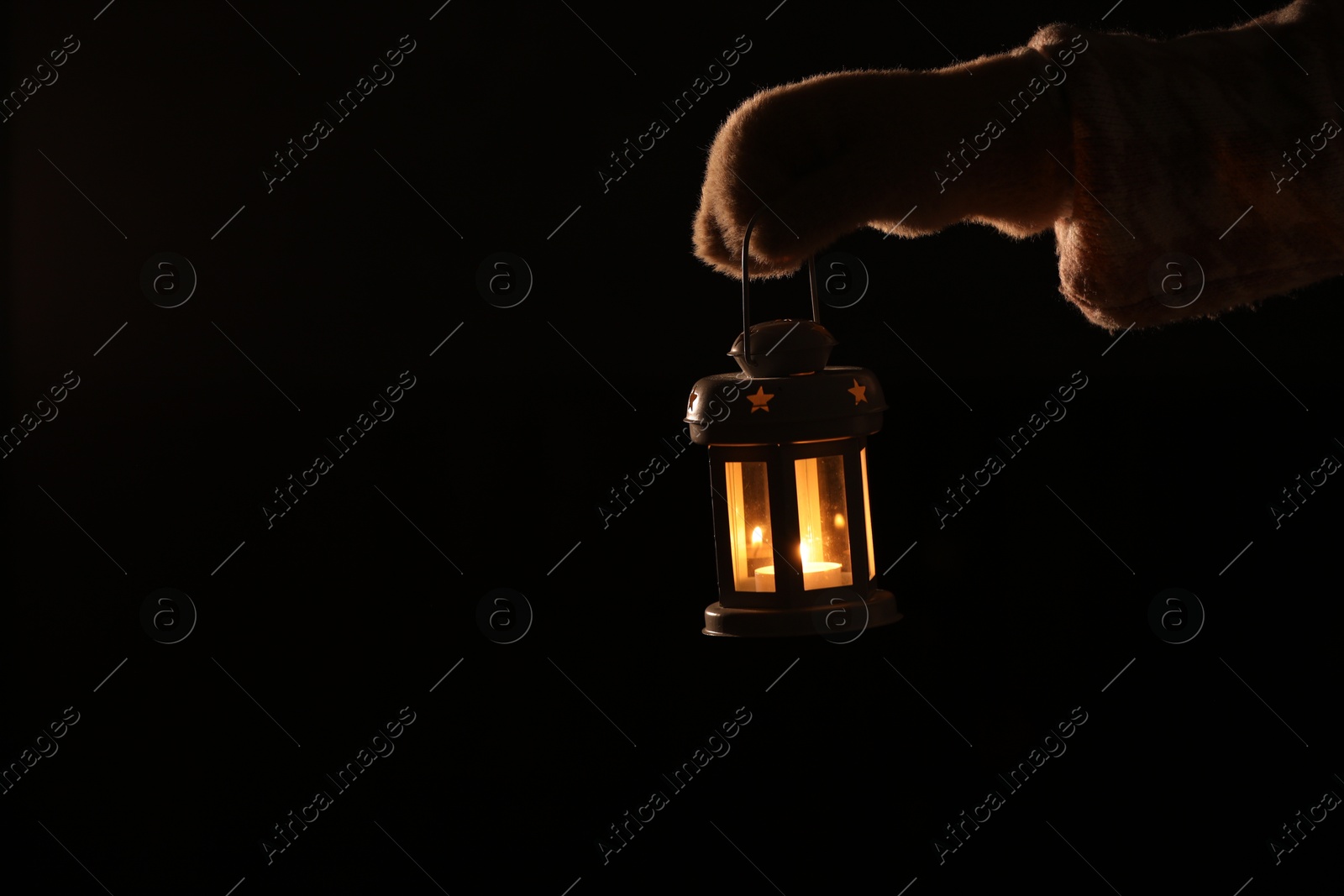 Photo of Woman holding Christmas lantern with burning candle in darkness, closeup. Space for text