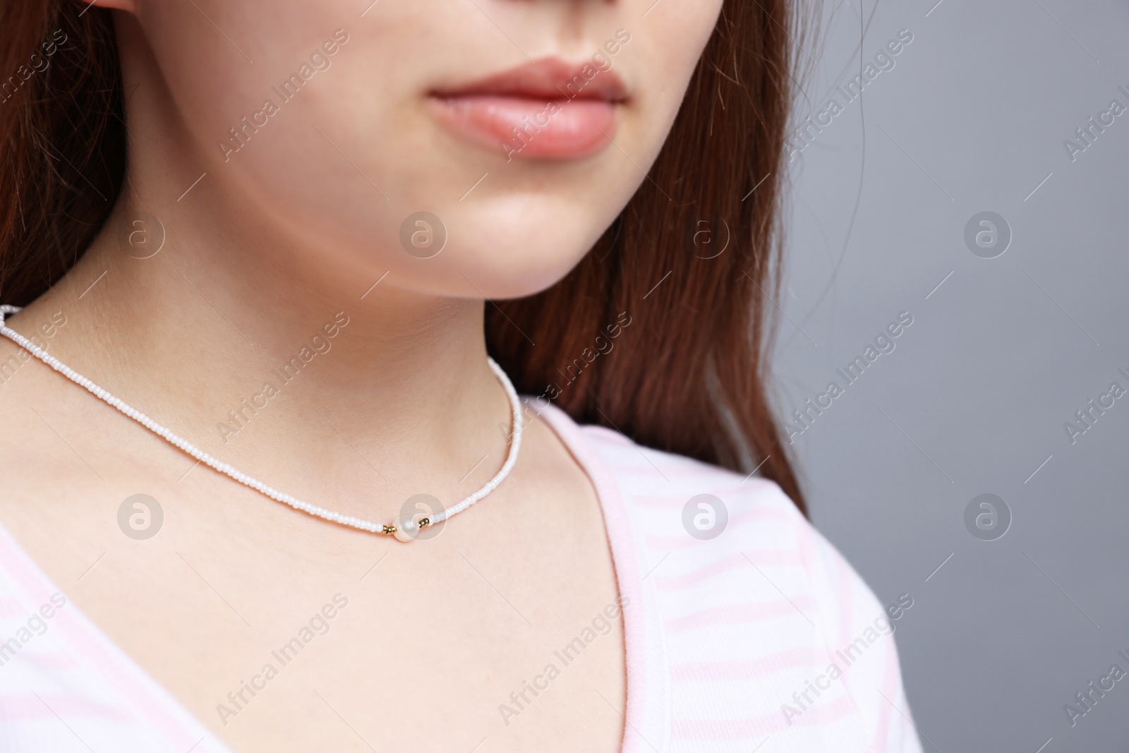 Photo of Teenage girl wearing stylish necklace on grey background, closeup