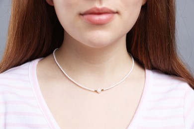 Photo of Teenage girl wearing stylish necklace on grey background, closeup