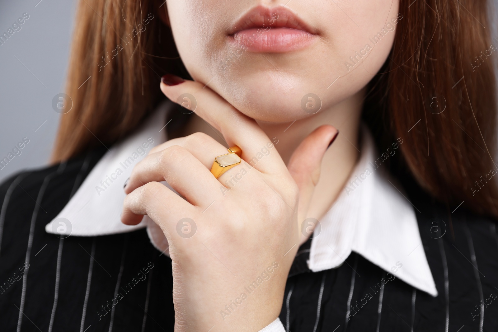 Photo of Teenage girl wearing stylish ring on grey background, closeup