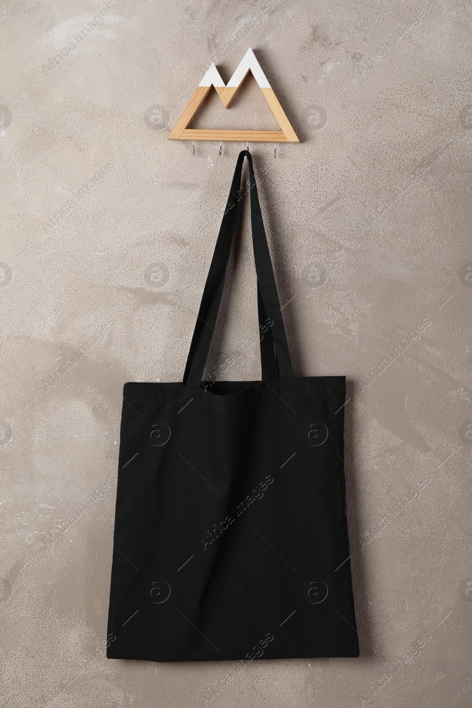 Photo of Black eco bag hanging on grey wall. Mockup for design