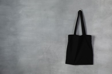 Photo of Black eco bag hanging on grey wall. Mockup for design