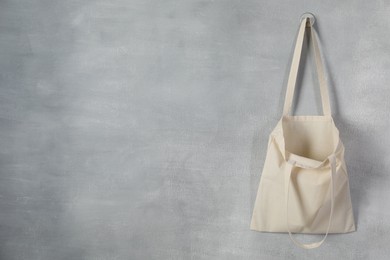 Photo of One eco bag hanging on grey wall. Mockup for design