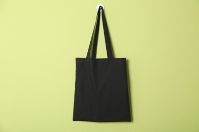 Photo of Black eco bag hanging on green wall. Mockup for design